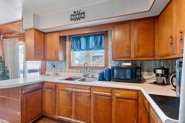 kitchen with brown cabinetry, light countertops, and a sink