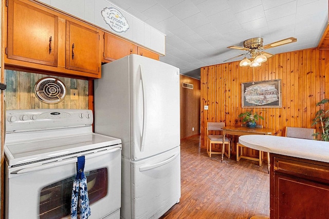 kitchen featuring light countertops, visible vents, brown cabinetry, light wood-type flooring, and white appliances