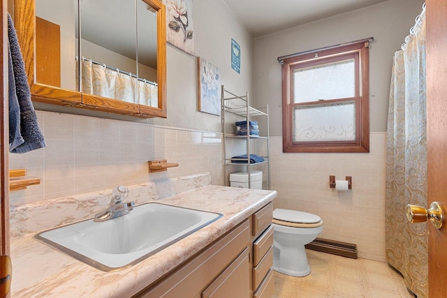 full bath featuring toilet, a wainscoted wall, vanity, tile walls, and tile patterned floors