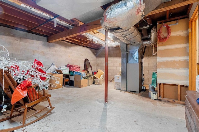 unfinished basement featuring heating unit and concrete block wall