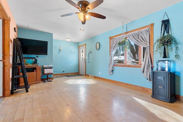 unfurnished living room featuring a ceiling fan, light wood-style flooring, and baseboards