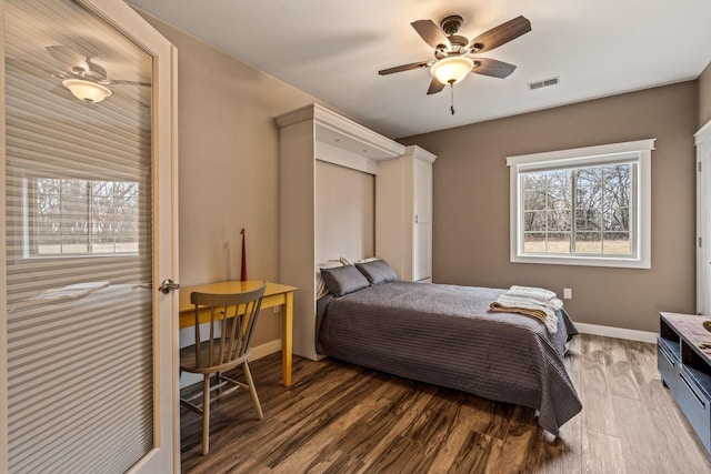 bedroom with a ceiling fan, wood finished floors, visible vents, and baseboards