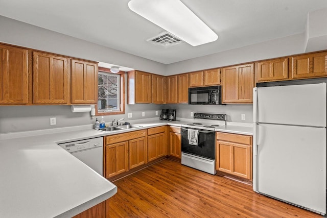 kitchen featuring light countertops, visible vents, a sink, light wood-type flooring, and white appliances