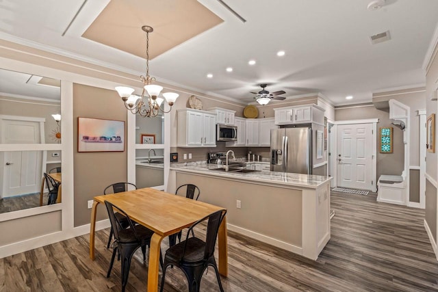 kitchen with stainless steel appliances, a sink, white cabinets, dark wood finished floors, and pendant lighting