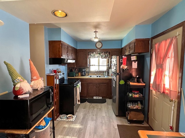 kitchen with range with electric stovetop, light countertops, freestanding refrigerator, a sink, and black microwave