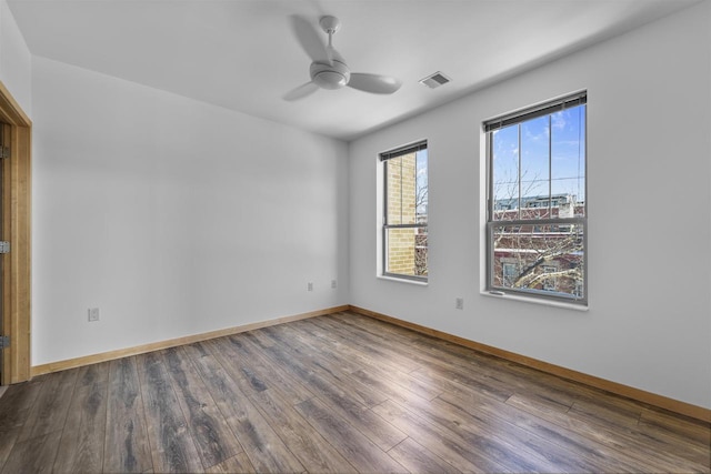 unfurnished room with a ceiling fan, visible vents, baseboards, and wood finished floors