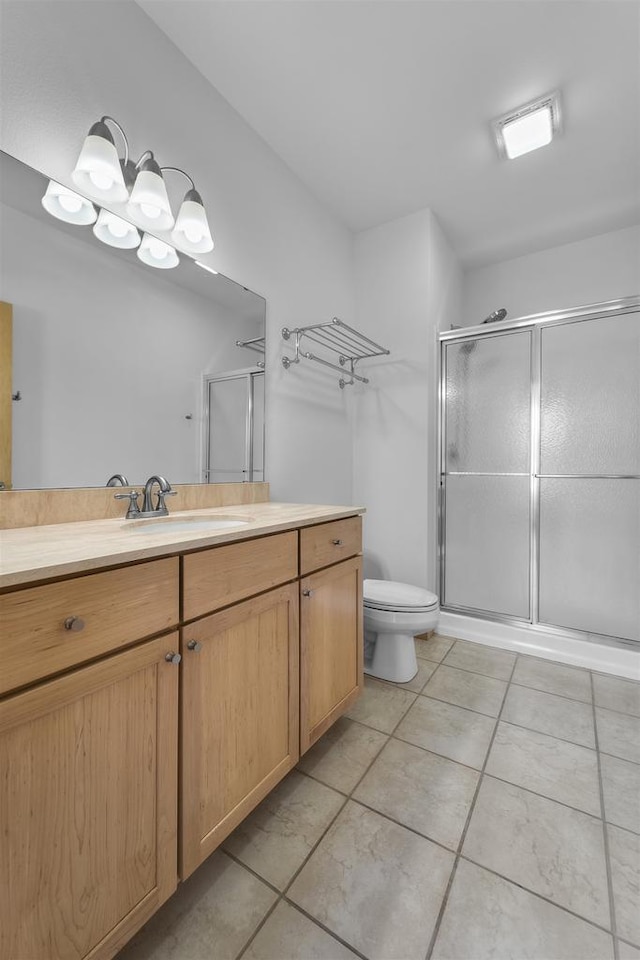 bathroom with tile patterned flooring, toilet, vanity, and a shower stall