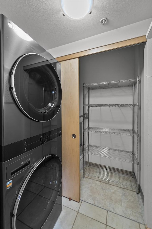 washroom featuring a textured ceiling, stacked washer and dryer, and laundry area