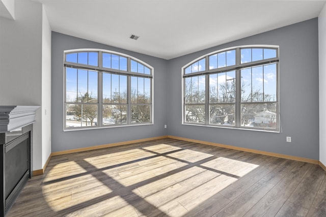 interior space featuring a fireplace, wood finished floors, visible vents, and baseboards