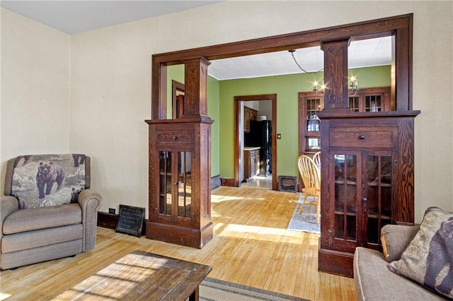 sitting room featuring an inviting chandelier, decorative columns, and wood finished floors