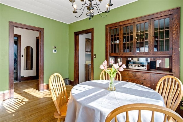 dining area with baseboards, wood finished floors, and an inviting chandelier