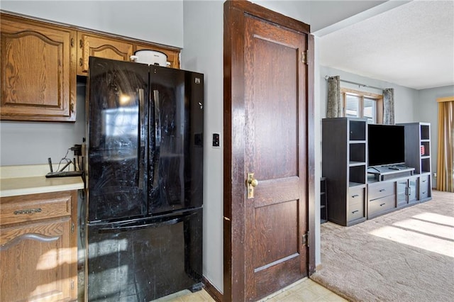 kitchen featuring brown cabinetry, freestanding refrigerator, and light countertops