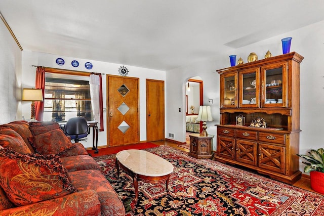 living area featuring arched walkways, visible vents, and wood finished floors