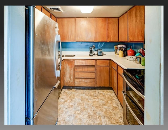 kitchen featuring light countertops, brown cabinetry, visible vents, and stainless steel appliances