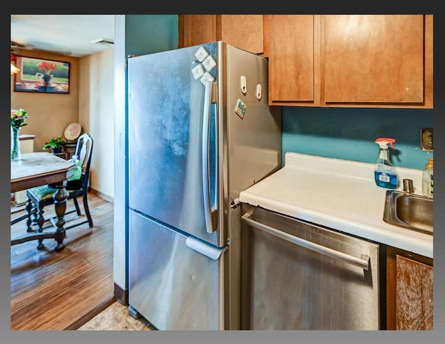 kitchen with brown cabinetry, visible vents, light wood finished floors, stainless steel appliances, and light countertops