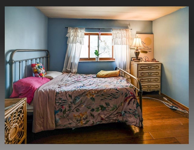 bedroom with baseboards and wood finished floors