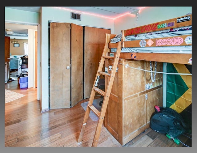 bedroom featuring a closet, visible vents, and wood finished floors