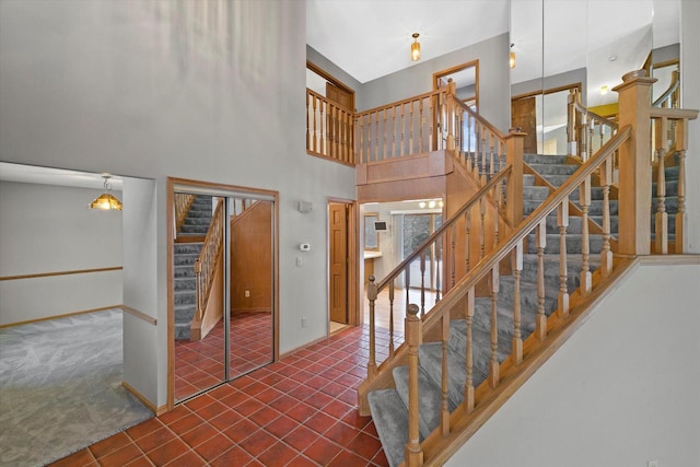 stairs with carpet floors, a high ceiling, baseboards, and tile patterned floors