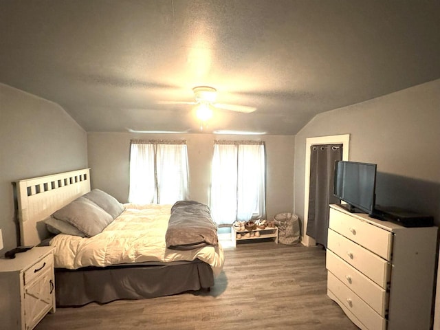 bedroom with lofted ceiling, a textured ceiling, a ceiling fan, and wood finished floors