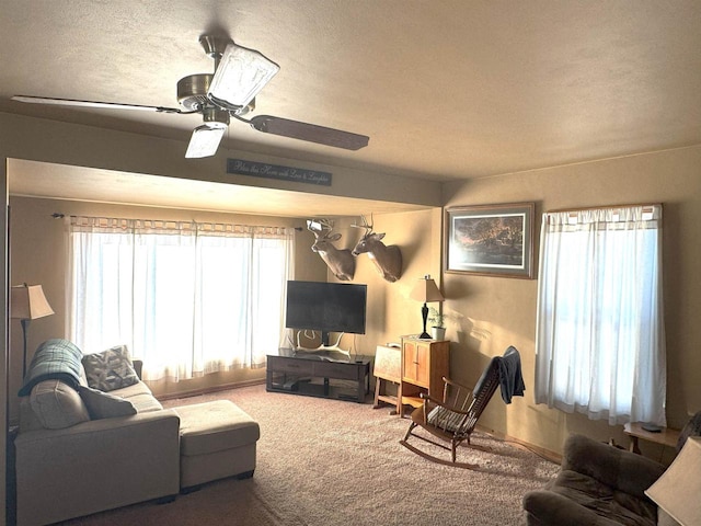 carpeted living room featuring a ceiling fan and a textured ceiling