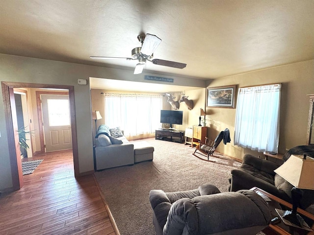 living area with ceiling fan, a textured ceiling, wood finished floors, and a healthy amount of sunlight