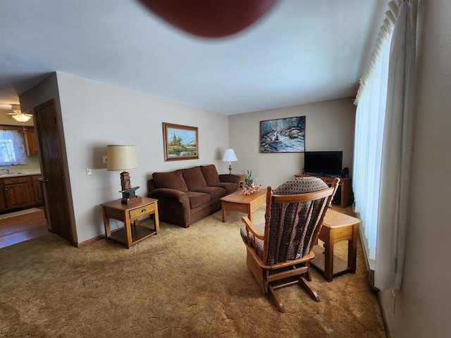 carpeted living room with a sink and baseboards