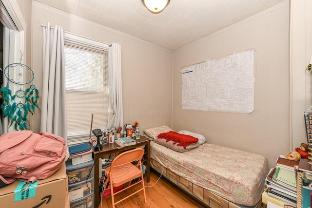 bedroom with ornamental molding and wood finished floors