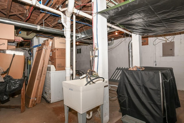 unfinished basement featuring a sink, washer / dryer, and electric panel