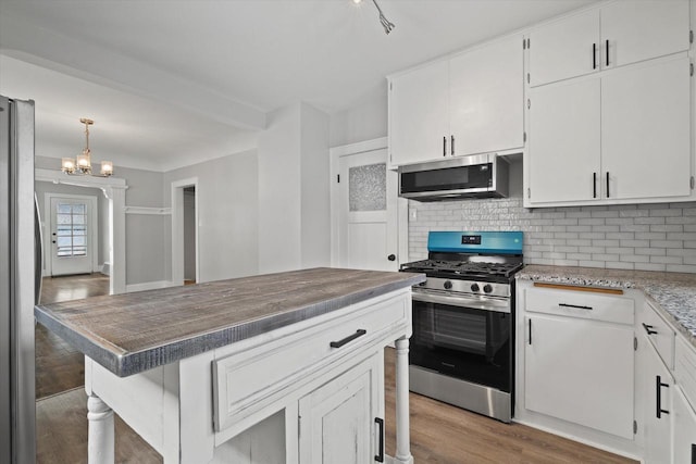 kitchen featuring decorative backsplash, a kitchen breakfast bar, stainless steel appliances, light wood-style floors, and white cabinetry