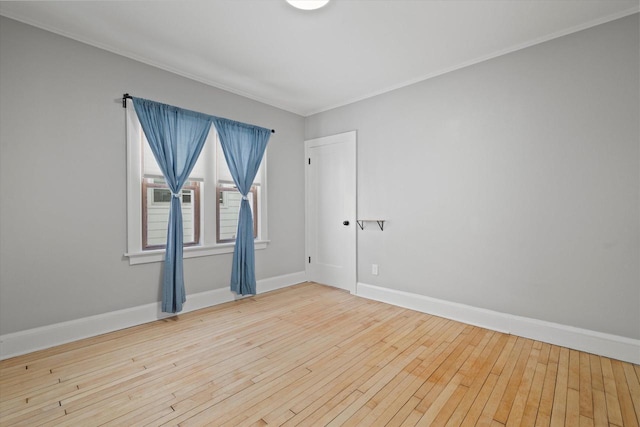 spare room with light wood finished floors, baseboards, and ornamental molding