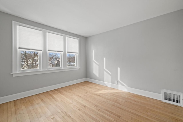 spare room with light wood-style flooring, visible vents, and baseboards