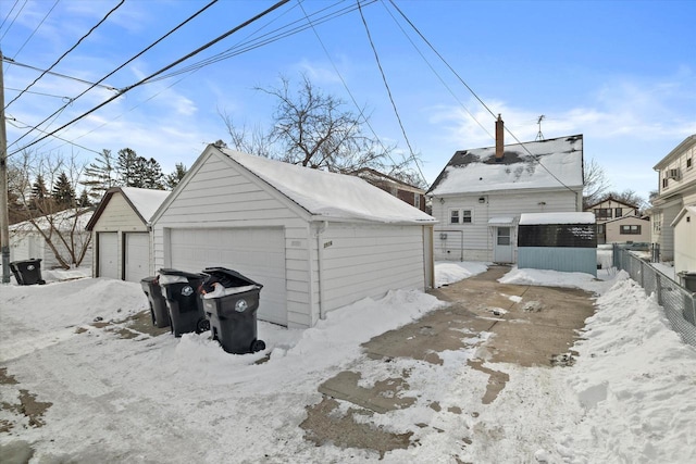 snow covered garage featuring a garage and fence