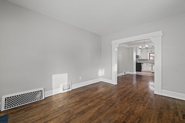 spare room featuring dark wood-style floors, a chandelier, visible vents, and baseboards