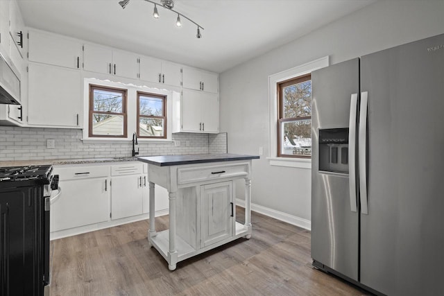 kitchen with appliances with stainless steel finishes, white cabinetry, and tasteful backsplash