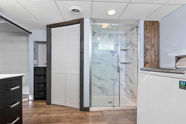 bathroom featuring washer / dryer, a marble finish shower, visible vents, wood finished floors, and vanity