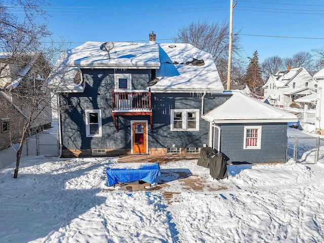 snow covered house featuring fence