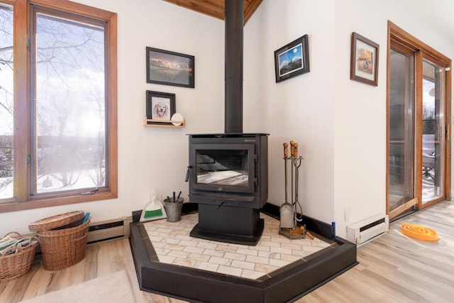 room details with baseboard heating, wood finished floors, a wood stove, and baseboards