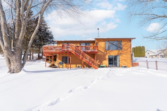 snow covered rear of property featuring stairs, fence, and a deck