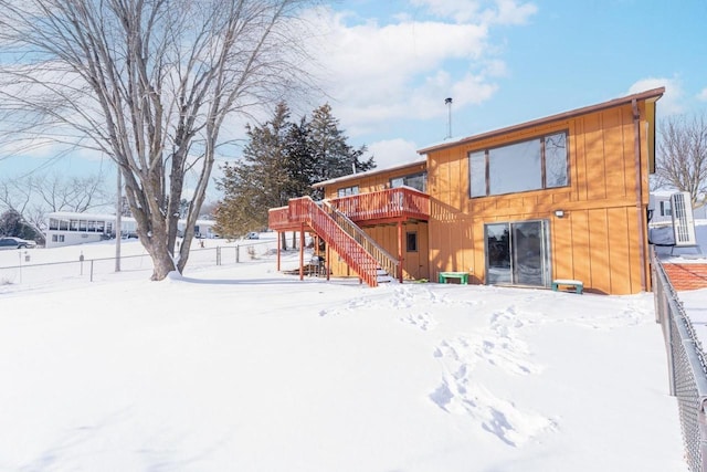 snow covered property with fence, a wooden deck, and stairs