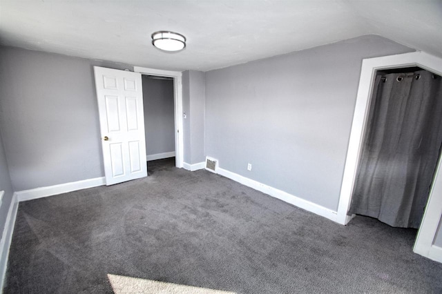 unfurnished bedroom featuring dark carpet, visible vents, and baseboards