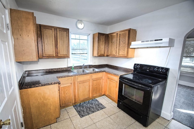 kitchen with under cabinet range hood, a sink, brown cabinets, black electric range oven, and dark countertops