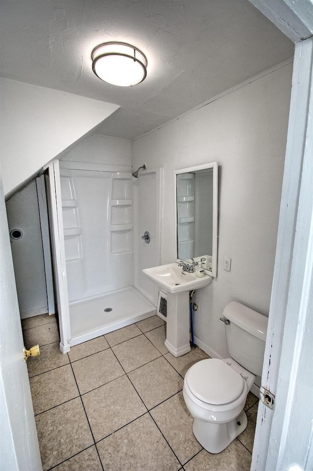 bathroom featuring a stall shower, tile patterned flooring, and toilet