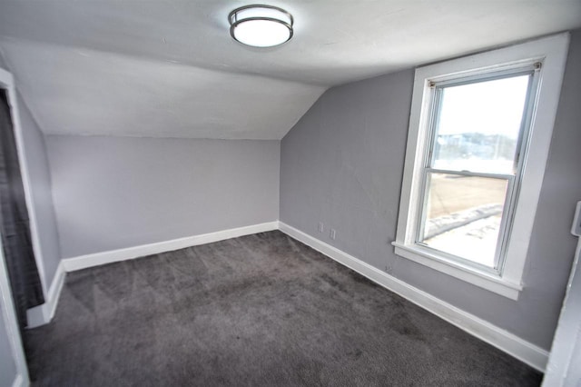 bonus room featuring vaulted ceiling, dark carpet, and baseboards