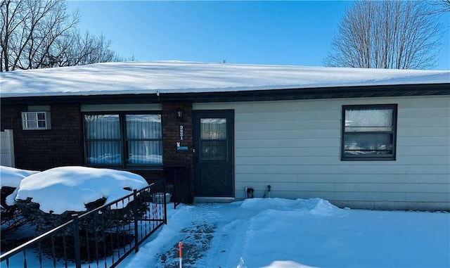 snow covered property entrance featuring brick siding