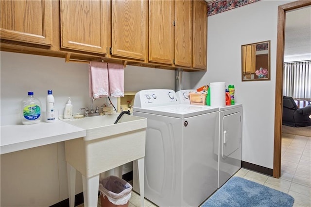 laundry room featuring light tile patterned floors, washing machine and clothes dryer, cabinet space, and baseboards