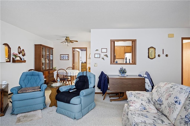 living room with a ceiling fan, light carpet, and a textured ceiling