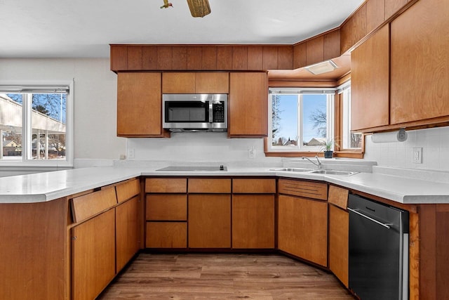 kitchen with stainless steel appliances, brown cabinets, light countertops, and a sink