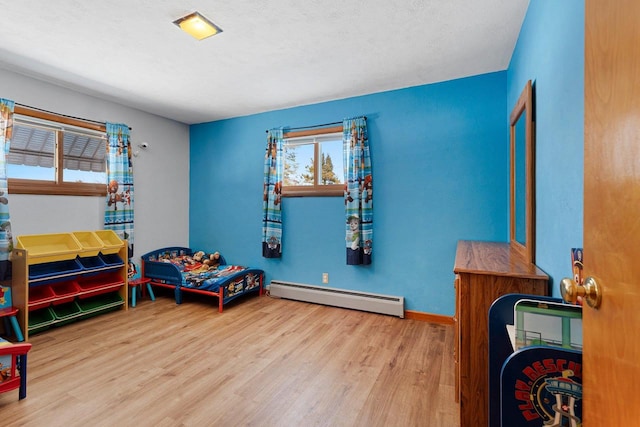 bedroom featuring light wood-type flooring, baseboards, baseboard heating, and a textured ceiling