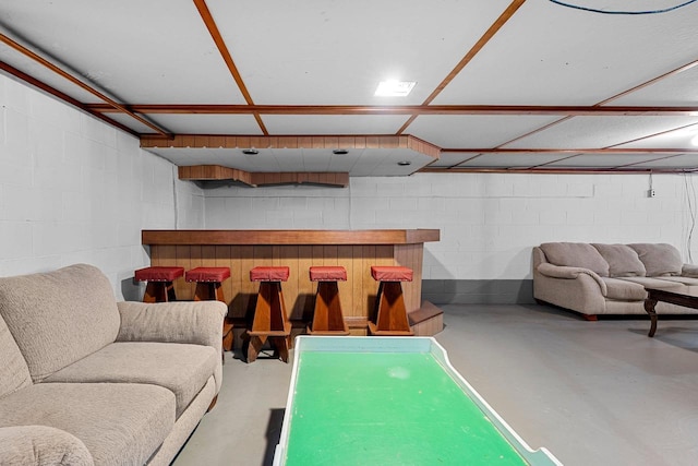 playroom featuring a bar, concrete floors, and concrete block wall