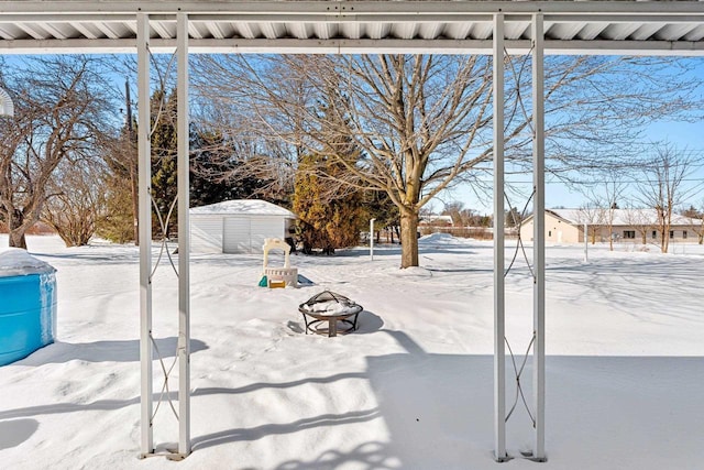 snowy yard featuring an outbuilding and a storage unit